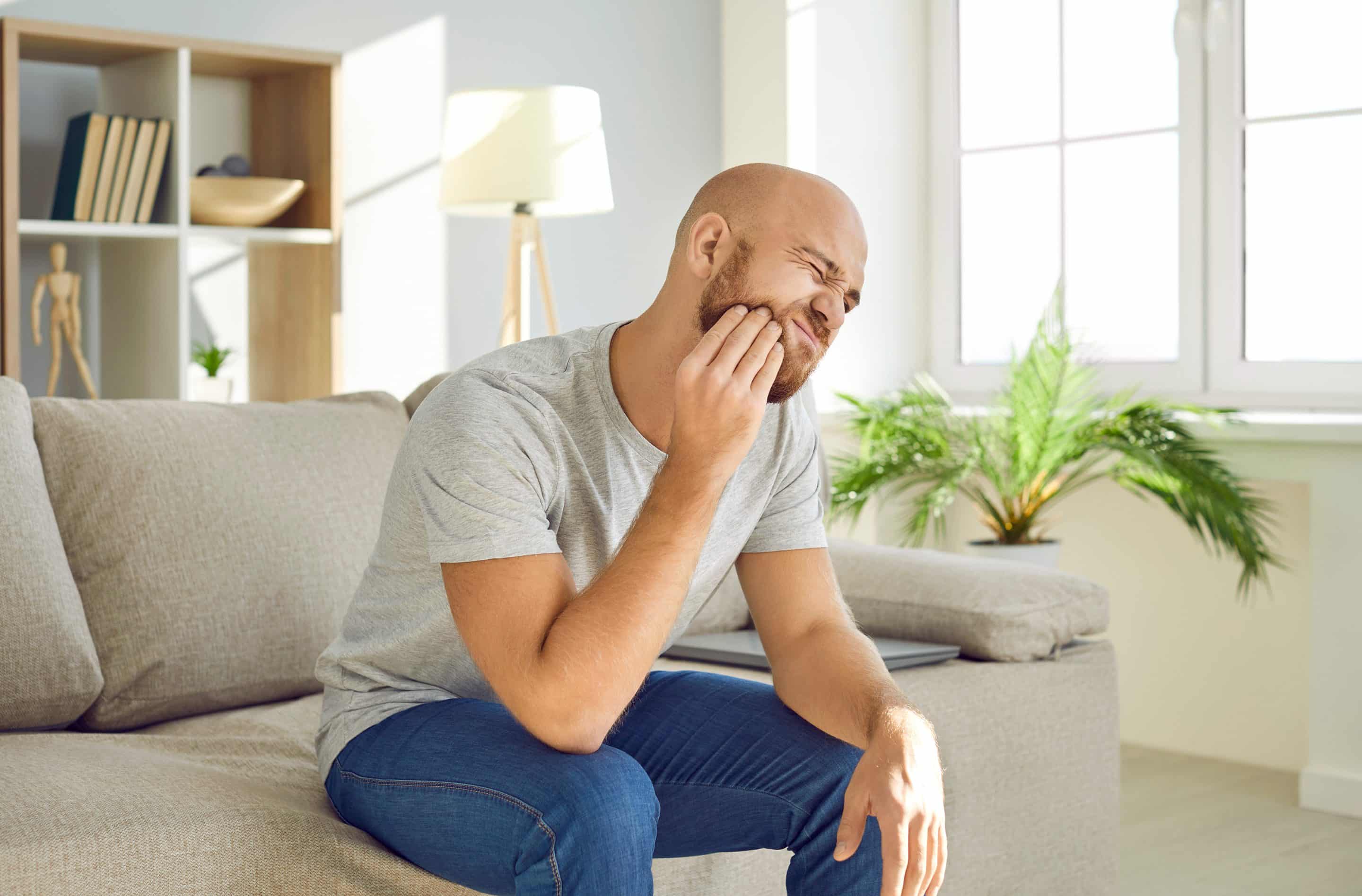 man sitting on couch with tooth pain in Falls Church