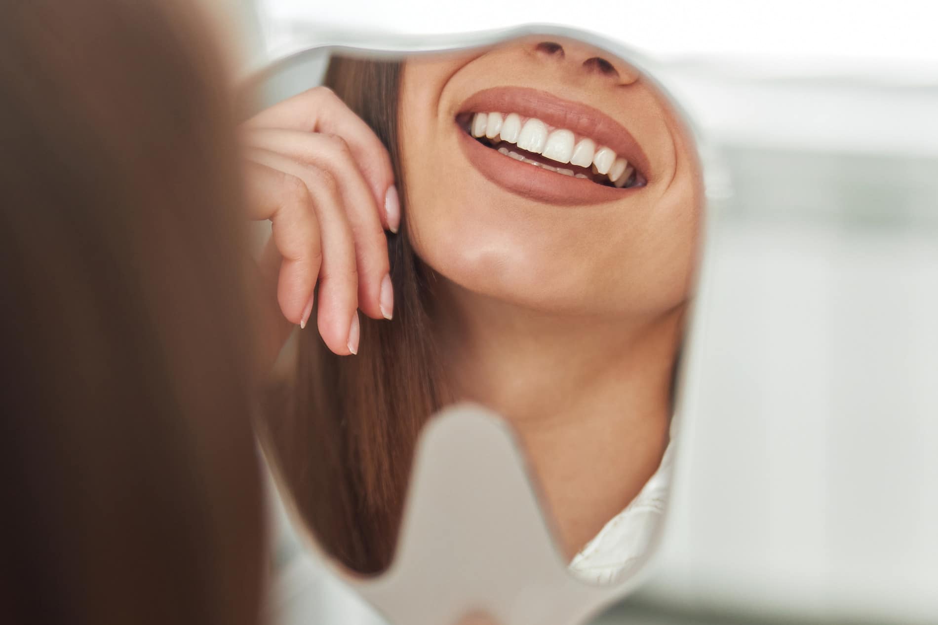 Woman looking in the mirror at her teeth bonding in Falls Church Va
